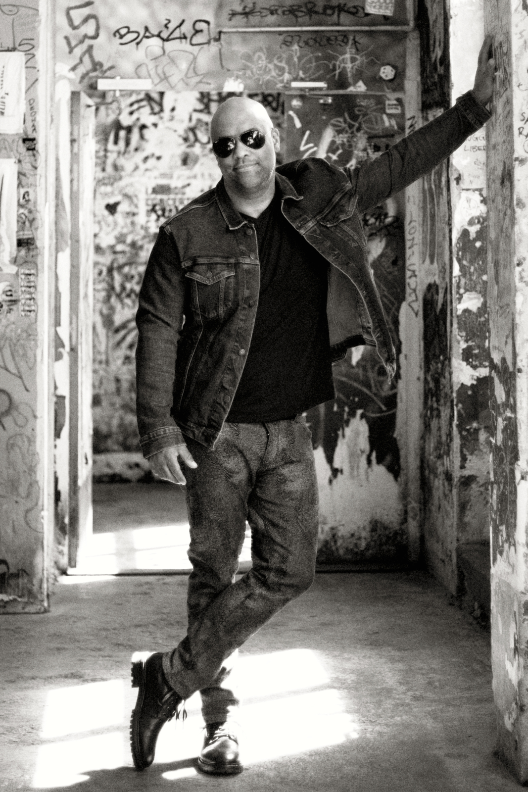 Mike Veny mental health speaker and patient advocate standing in a graffiti-covered urban space, wearing a denim jacket and sunglasses, conveying resilience, confidence, and authenticity.