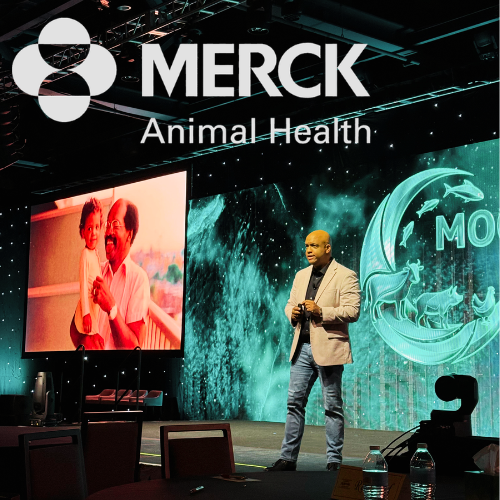 Mike Veny pharmaceutical and healthcare keynote speaker presenting on workplace mental health and resilience at a Merck Animal Health corporate event, speaking on stage in front of a professional audience with branded conference visuals.