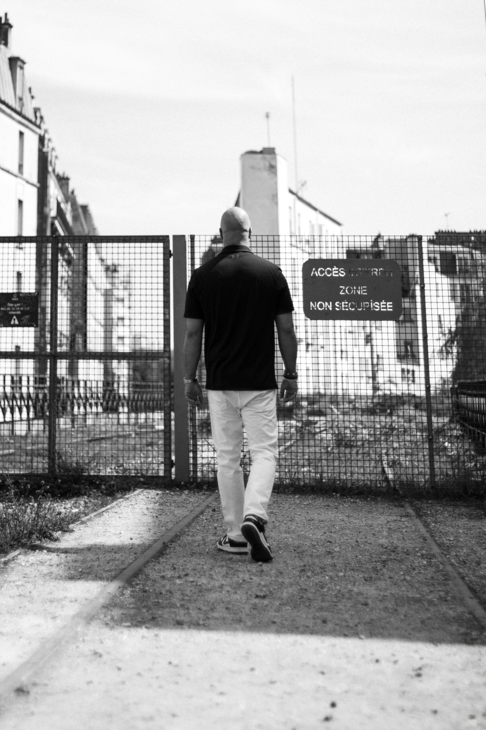 Top healthcare speaker Mike Veny walks through an urban outdoor setting in a black-and-white portrait for healthcare conference, workplace wellness, and mental health event promotion.